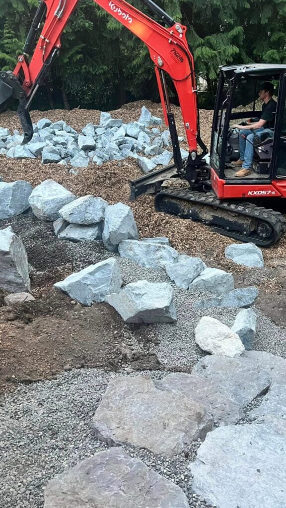 an excavator placing landscaping rock
